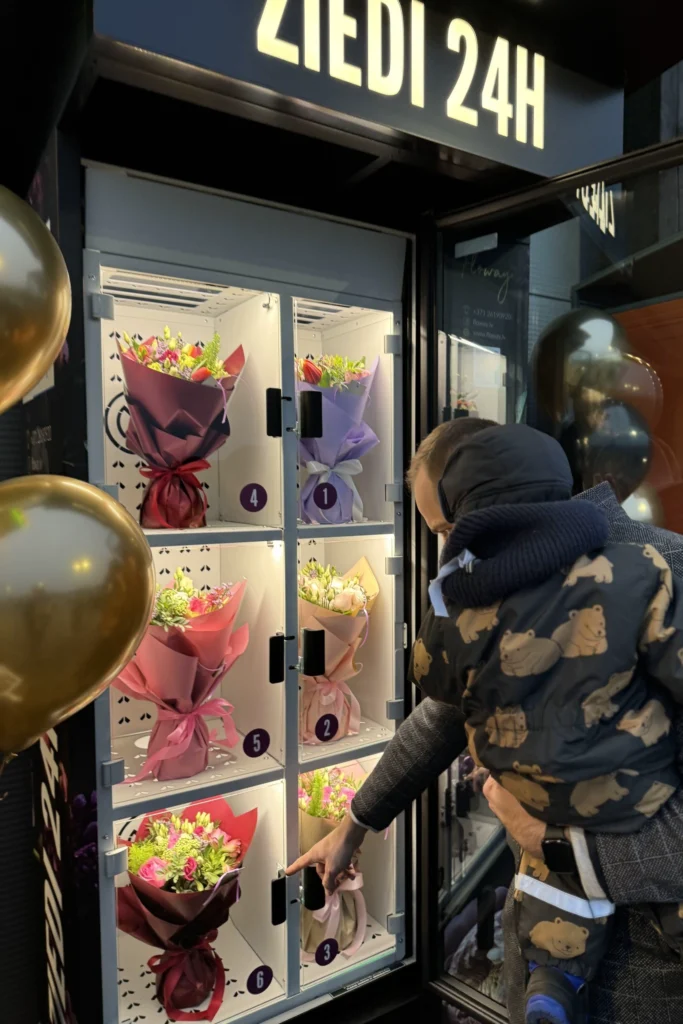 customer choosing bouquet from flower vending machine 24/7 Flowey Riga