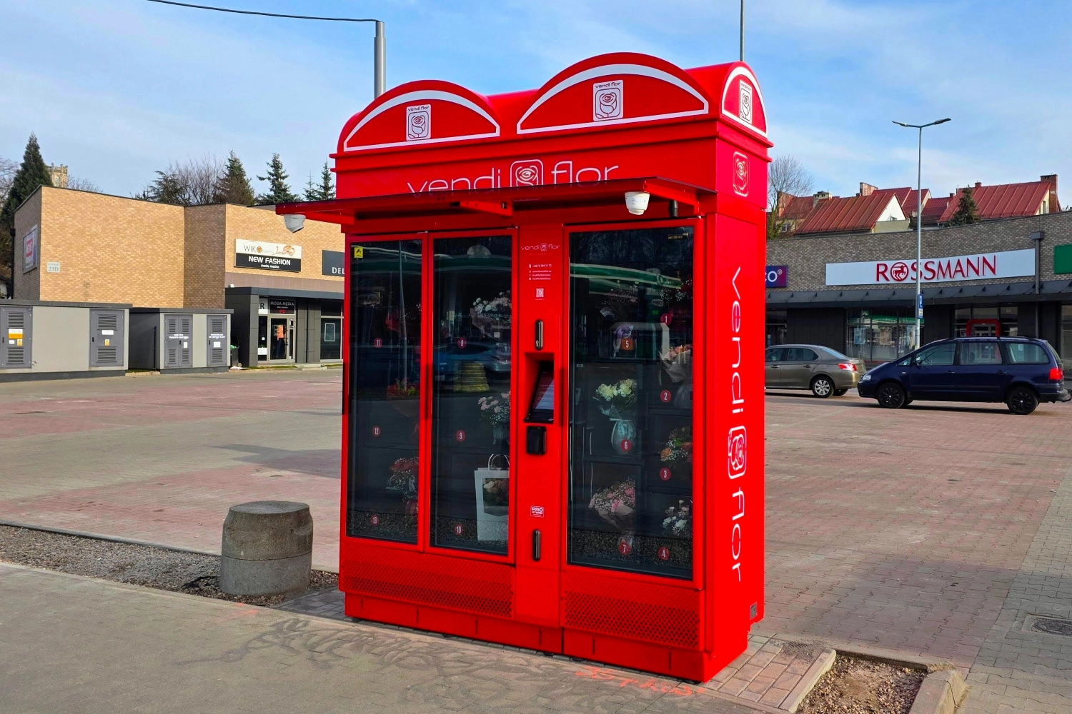Czerwony Kwiatomat VendiFlor z podświetlanymi kasetonami reklamowymi i oznakowaniem bocznym, prezentujący możliwości personalizacji nowoczesnych automatów do sprzedaży kwiatów.