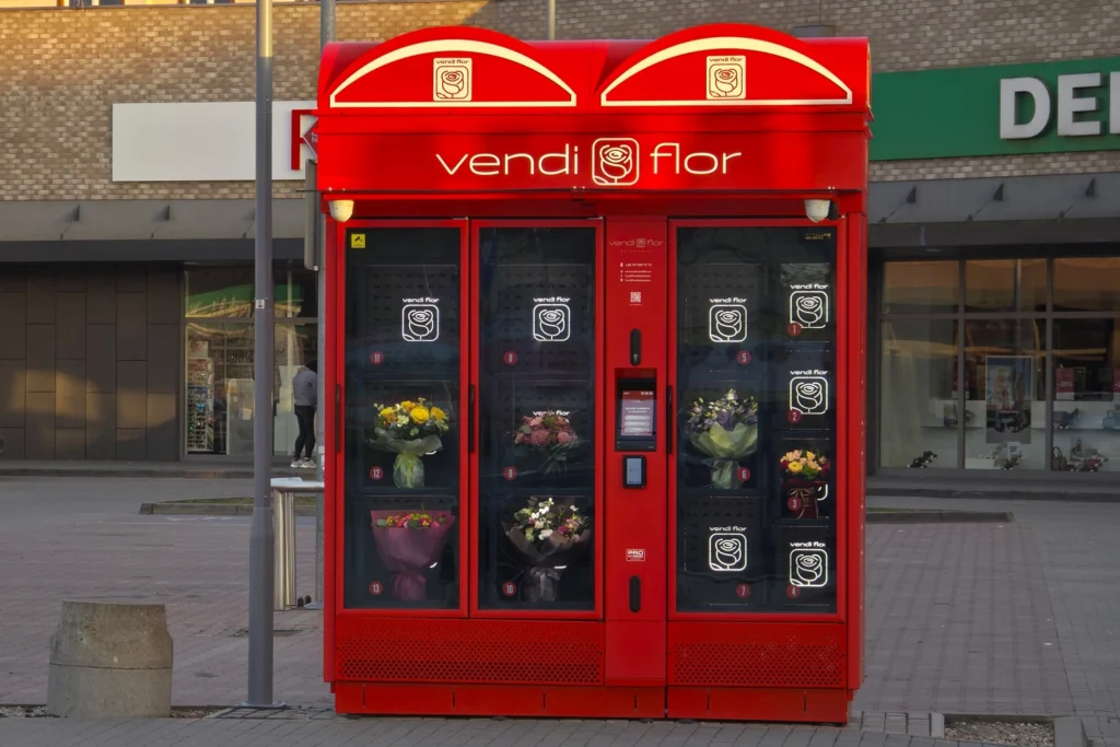 Red VendiFlor flower vending machine with a custom exterior design and illuminated advertising lightboxes, showcasing the personalization possibilities of modern flower vending machines.